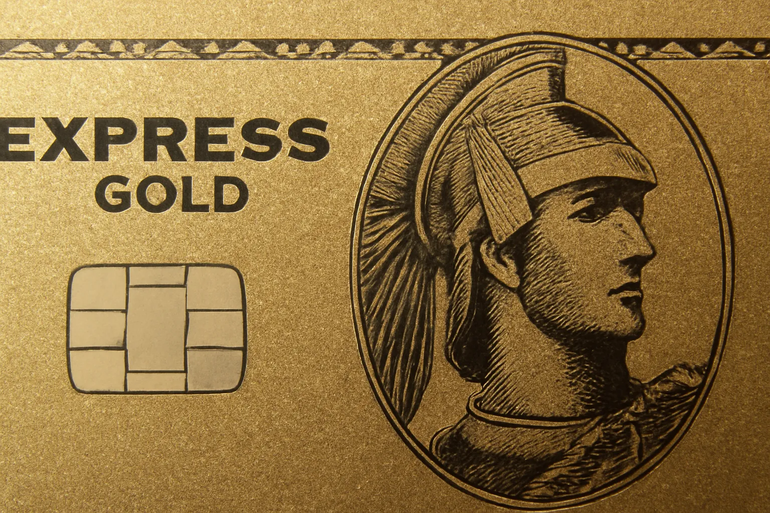 Close-up of a gold credit card, highlighting intricate details of the design, possibly representing the American Express Gold Card.